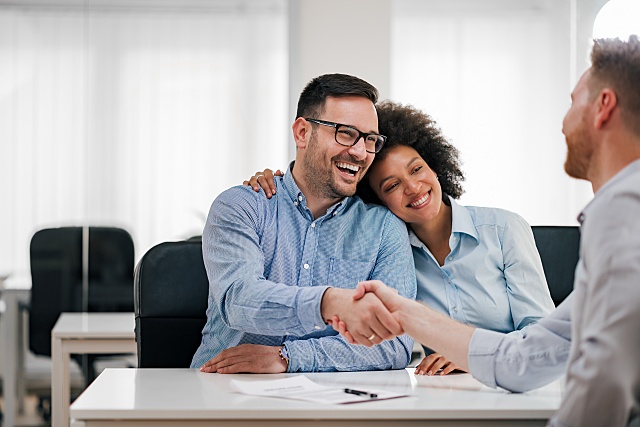 happy couple at a bank shaking hands with a banker